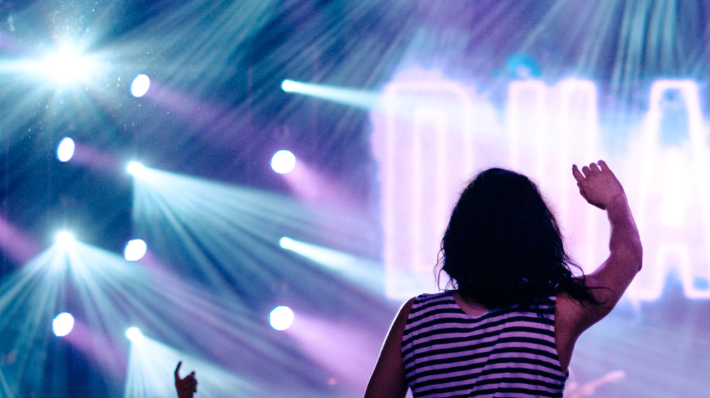 back of woman wearing striped shirt enjoying concert